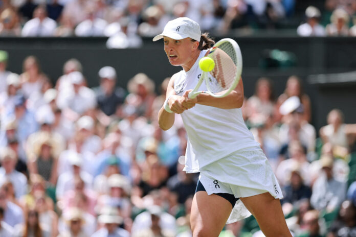 Iga Swiatek plays a backhand on Centre Court during her Wimbledon 2026 first-round match