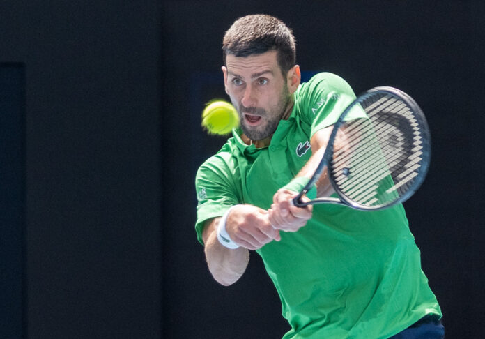 Novak Djokovic hits a high return at the Australian Open