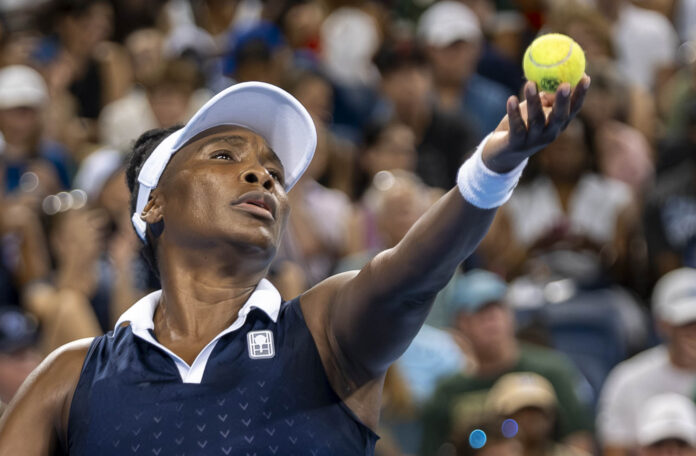 Venus Williams serves during her doubles match with Serena at the Cincinnati Open